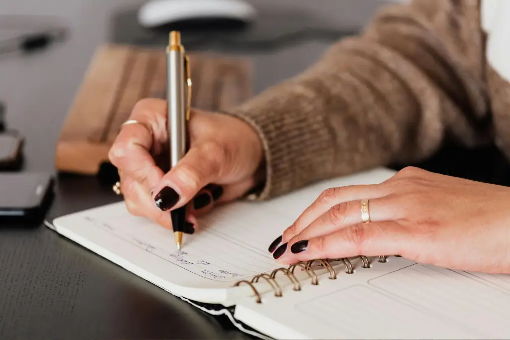 Person writing in a notebook with pen. Person writing in a notebook with pen.