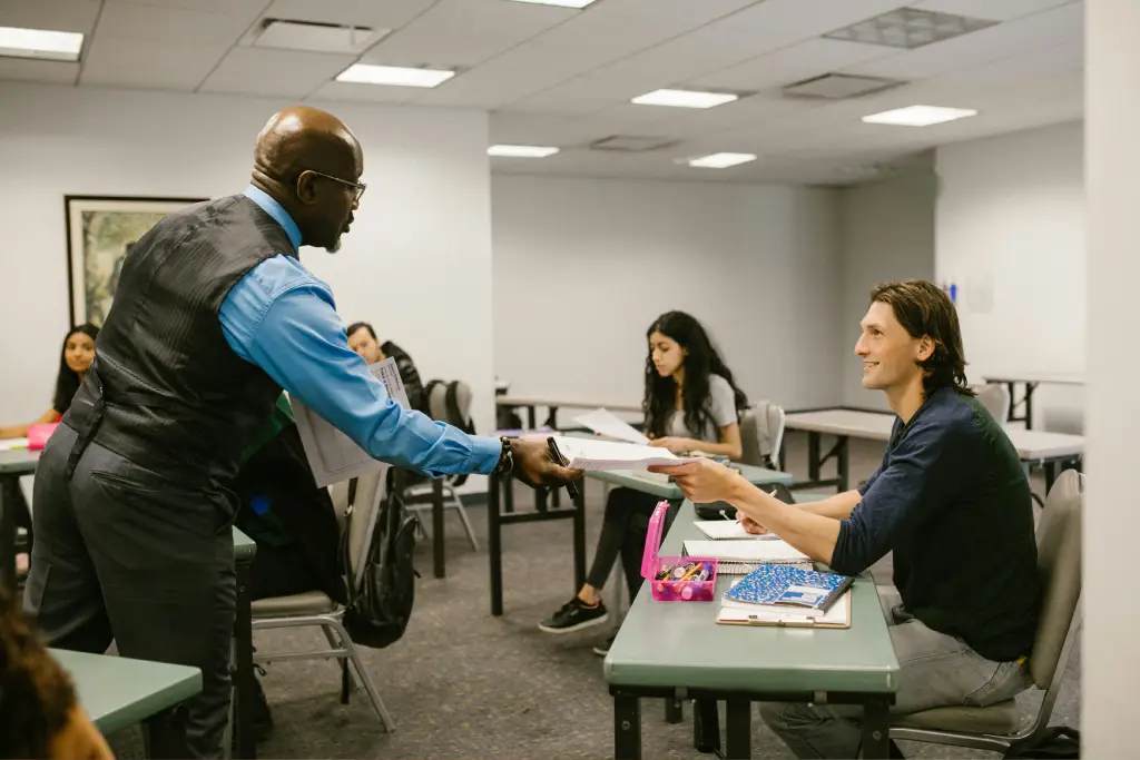 Teacher handing papers to smiling student. Teacher handing papers to smiling student.