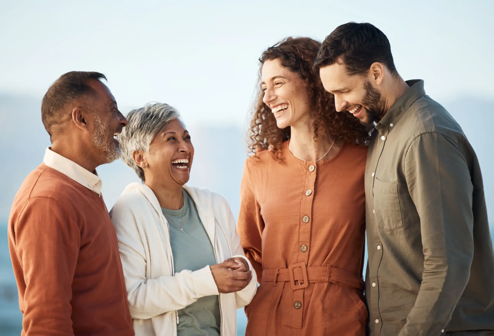 Group of people laughing together outdoors.