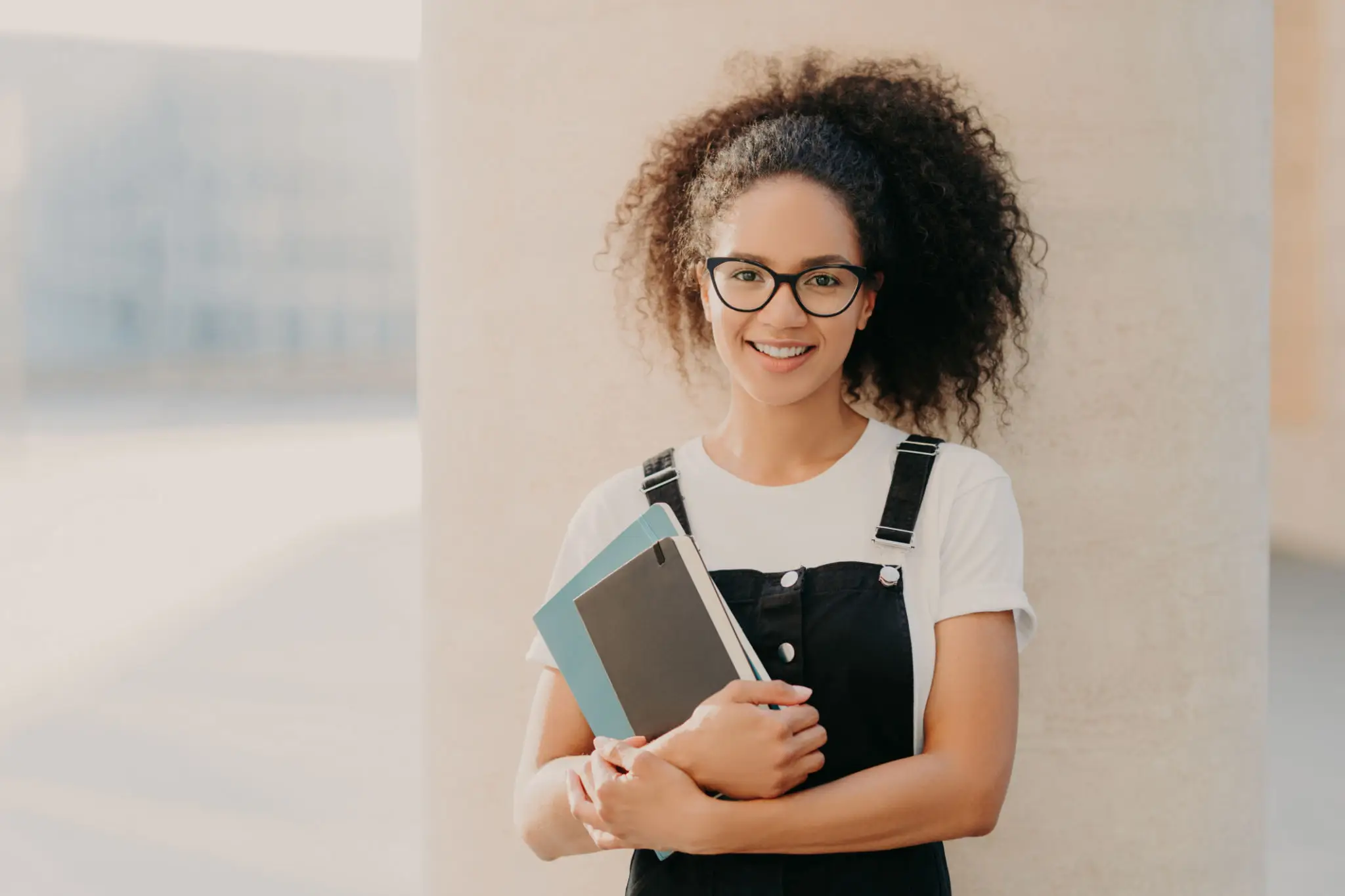 Smiling person holding books, wearing glasses. Smiling person holding books, wearing glasses.