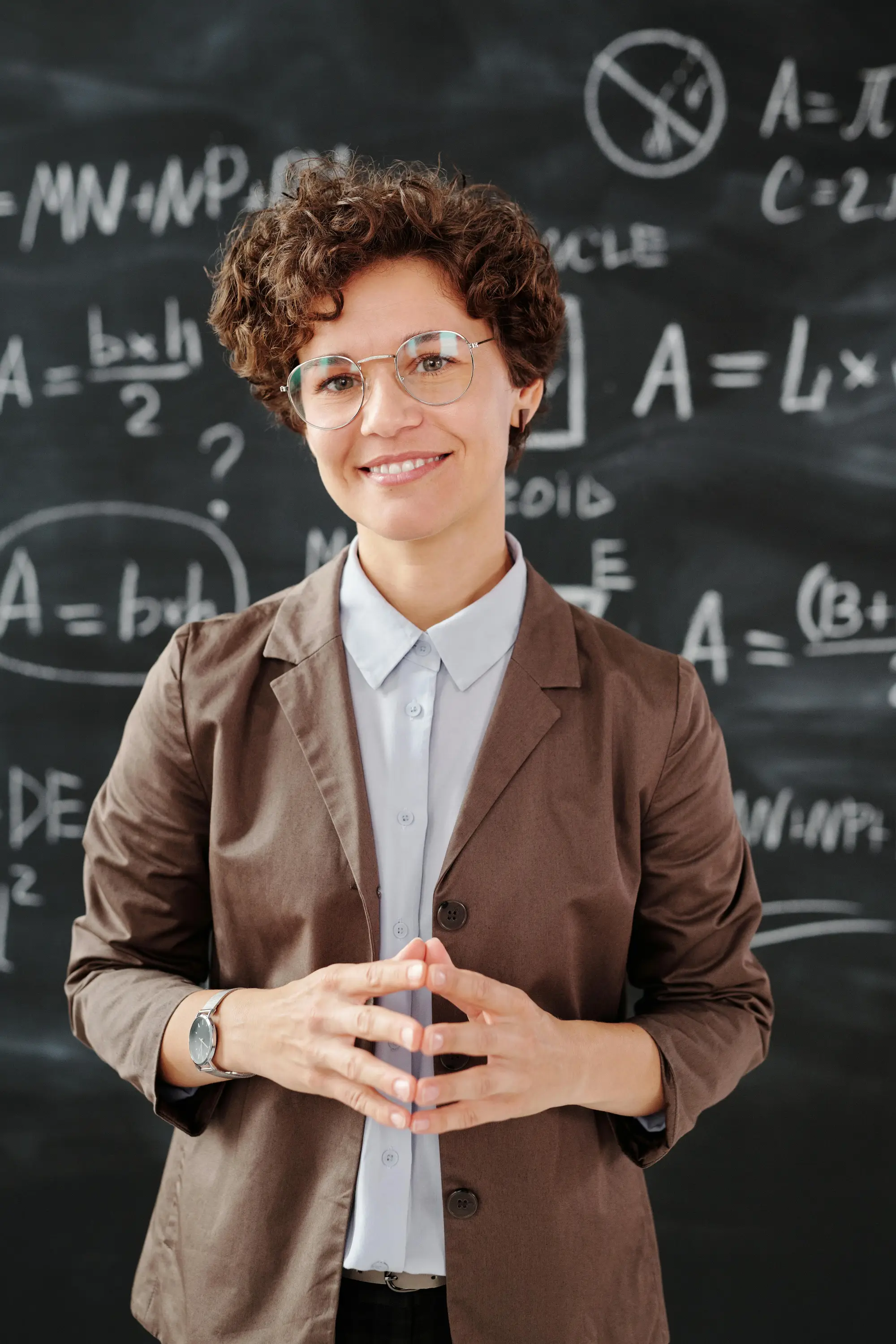 Teacher standing in front of chalkboard equations. Teacher standing in front of chalkboard equations.