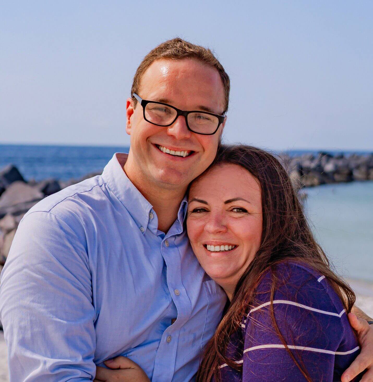 Couple smiling by the seaside rocks.