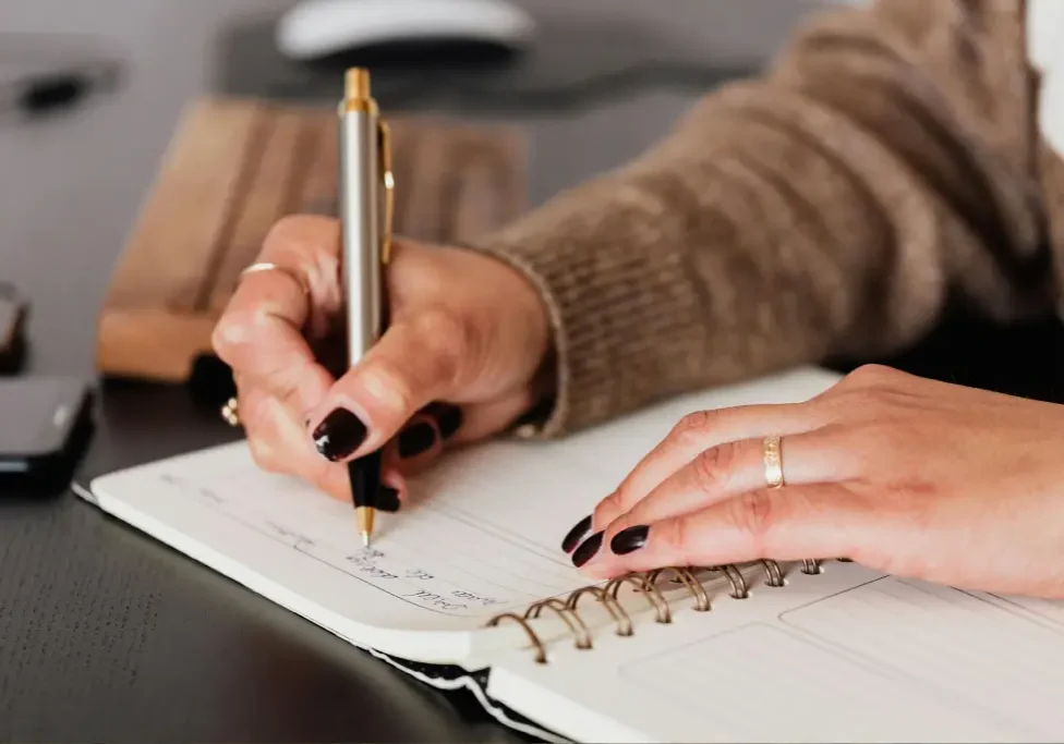Person writing in a notebook with pen.