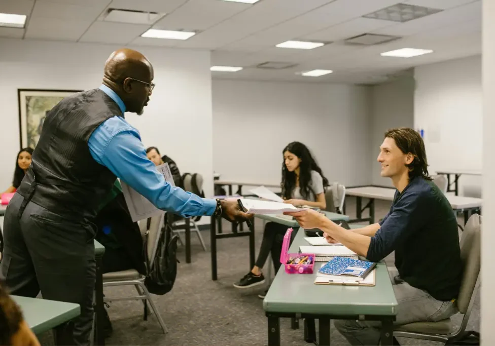 Teacher handing papers to smiling student. Teacher handing papers to smiling student.