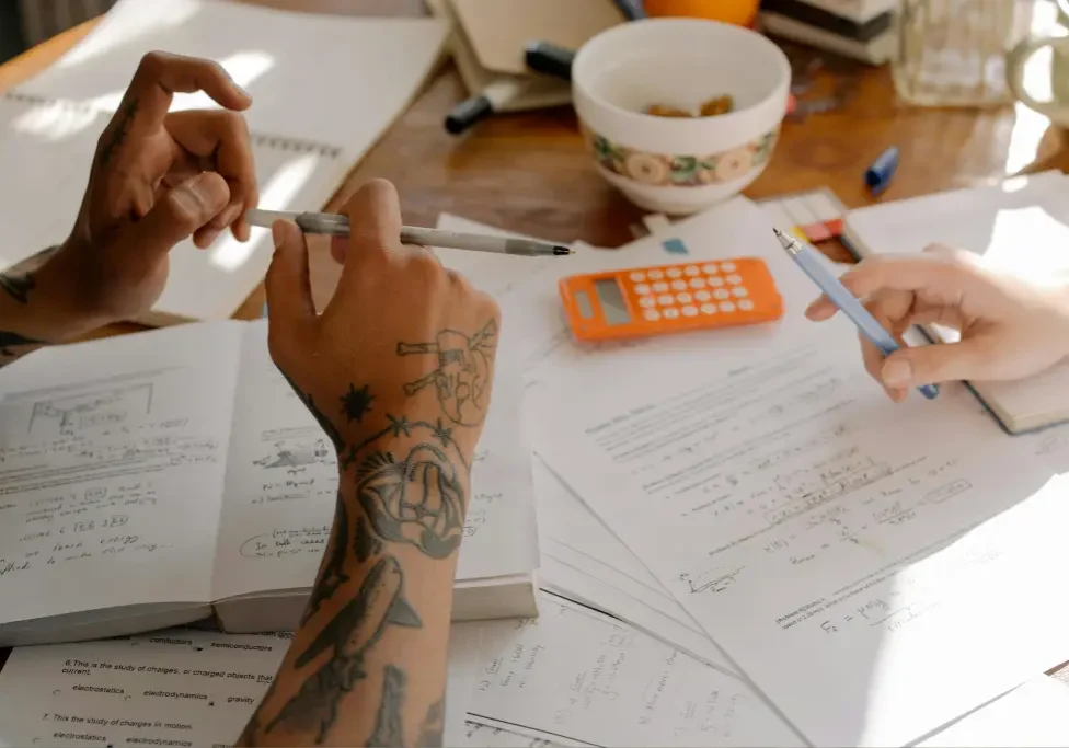 Hands studying with books and calculator.