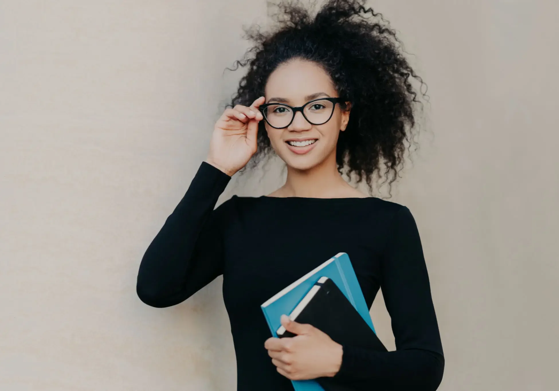 Woman with glasses holding a notebook, smiling. Woman with glasses holding a notebook, smiling.