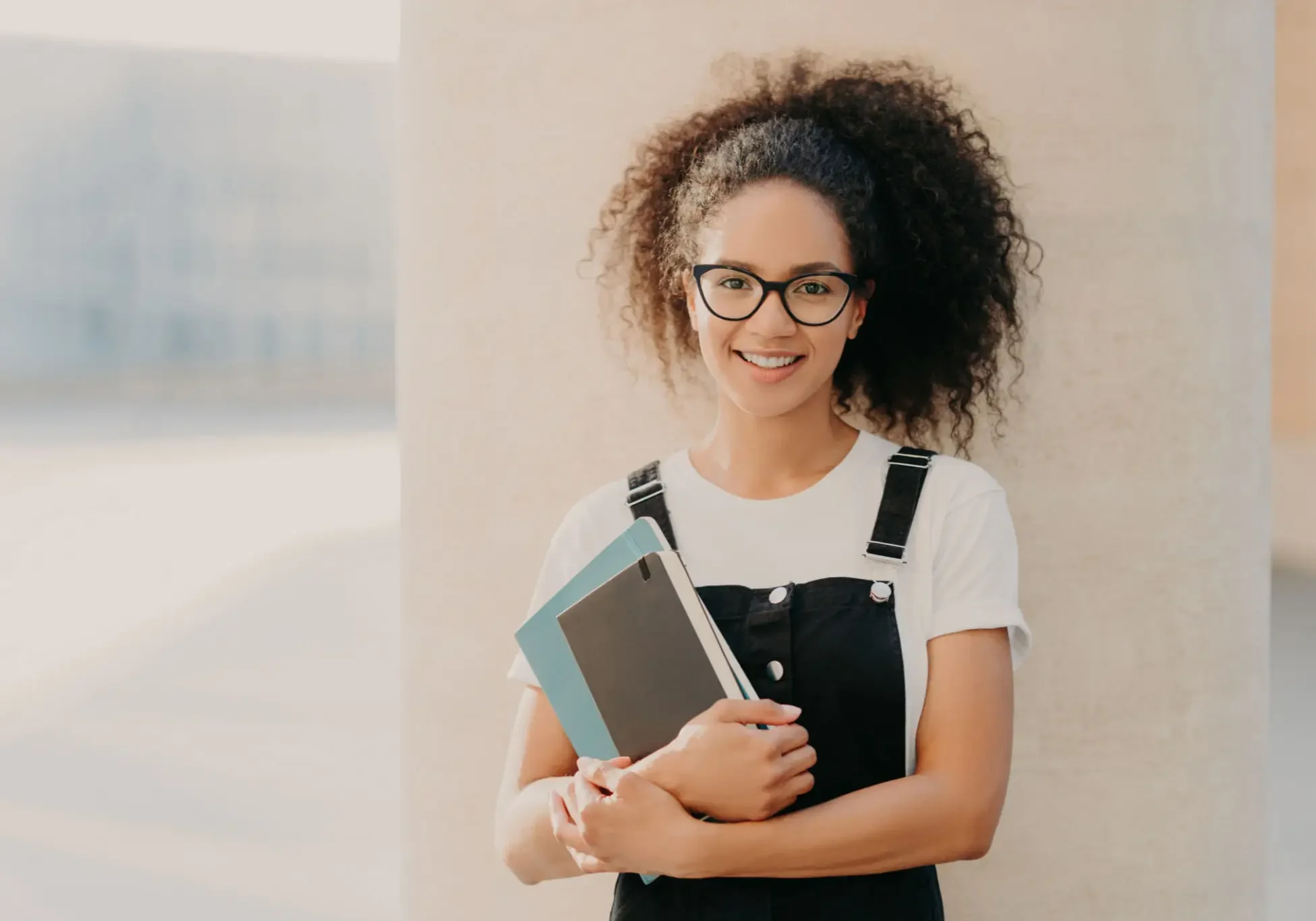 Smiling person holding books, wearing glasses. Smiling person holding books, wearing glasses.